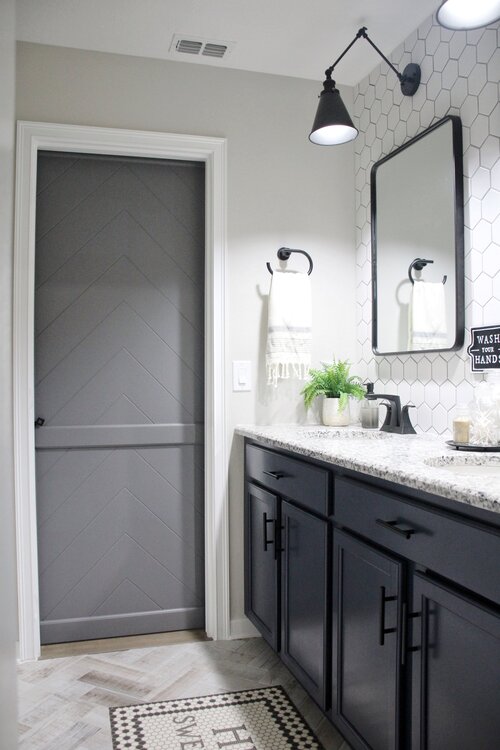 View of grey bathroom barn door with a black lock from inside the bathroom.